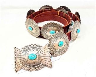 #590 • Captivating Contemporary Turquoise and Sterling Silver Concho Belt. Here is a captivating contemporary turquoise and sterling silver concho belt. This is a well crafted concho belt set with gorgeous turquoise cabochons. The buckle and (10) conchos have beautiful hand stamped designs accenting each turquoise setting. It looks to be barley worn and well taken care of. It is on a new tobacco (brownish-red) harness leather belt and is stamped as sterling. Maker: Hallmarked Raincloud JR. The conchos measure 3-1/8 inches wide X 2-3/4 inches long. The buckle is 3-5/8 inches wide X 2-1/2 inches long. The belt itself is 60 inches long overall but can be adjusted to size. Weight is approx. 520.9 g. which would include everything.
