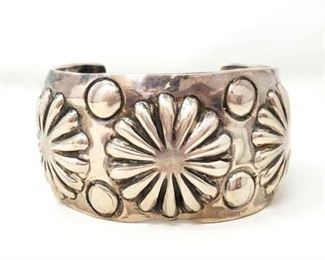 #610 • Huge Heavy Hand Tooled Vintage Native American Navajo Sterling Silver Shell Bracelet Cuff: This is an exceptional vintage Navajo hand repoussed silver concho bracelet. This piece contains a beautiful plethora of hand repoussed silver shells that are in the shapes of concho works. Situated throughout the shells are wonderful silver plant and sun stampings. Signed by Navajo artist,Emerson. Sterling silver, marked. Cir. 1970's+. Sturdy 73.1 grams. Approx Cuff Size 2.5" Approx Width 2.5"