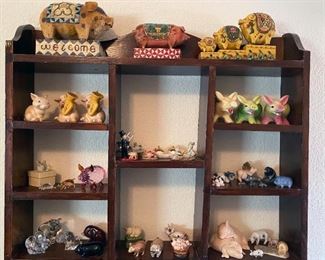 Assorted small pig figurines on wooden curio shelf