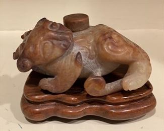 Carved brown jade nephrite lion on teak stand. 