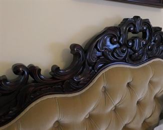 Ornately carved headboard on queen sized bed.