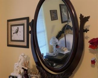 Tilting mirror with carving on base on dresser.