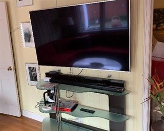 modern glass and steel table with wavy frosted glass shelves/ entryway table above: LG 60SJ8000 60" (2017) SUPER UHD SMART TV 4K HD with extension wall mount bracket (buyer is responsible to have a qualified person remove) 