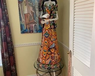 5' tall Talavera Catrina from the Catrina Shop in Houston, 22" diameter across base standing atop a  stainless metal and round glass measuring 22" tall and and 25" in diameter.  Abstract cubist cityscape giclee by Kirby Rogere (Louisiana- Texas artist 1929 - 2006) measures 24" by 30"