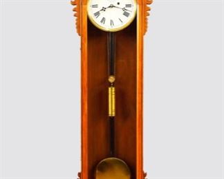 Reproduction of a E. N. Welch "No. 11" model Regulator wall clock.  8-day time only weight driven movement with maintaining power and painted metal dial, Roman numerals and subsidiary seconds.  Walnut case with a shaped crest above a single arched molded door with carved ears over a shaped drop with carved detail.  Original finish with minor wear, running when cataloged.  18 x 8 x 84 1/2" high overall.
