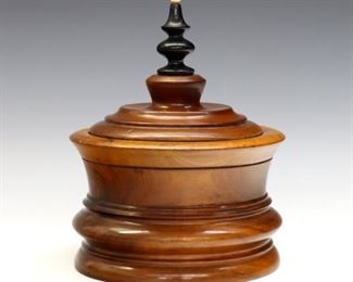 A late 19th century Cherry treenware covered box.  Turned design with incised rings and Black painted finial.  Refinished, some surface wear and minor damage to edges.  5 1/2" diameter x 7 1/2 high overall.  ESTIMATE $100-150
