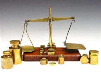 A Victorian period British postal or jeweler scale and additional weights.  Includes a small Brass balance scale on Walnut base with seven inset weights, and seven additional Bronze & Brass weights ranging from 2/3 oz to 1kg.  Some bend to hangers and wear overall.  Scale is 9 x 4 x 8 1/4" high overall.  ESTIMATE $200-300
