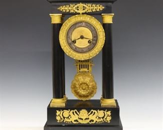 An early 20th century French Empire Period portico clock.  8-day time and strike movement marked "ACD" with a cast Bronze dial and Roman numerals.  Ebonized case with four turned columns, Gilded Bronze Capitols and pendulum.  Case repainted with some wear, damage and old repairs, dial wear, columns loose from pediment, running when cataloged.  16 3/4" high.  ESTIMATE $300-500
