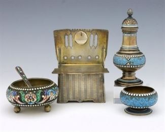 Four turn of the century Russian Sterling Silver salt cellars and shakers.  Includes a salt and pepper set with Blue enamel decoration, an open salt cellar with multi-color enamel decoration, and a salt box in the form of a throne chair with etched decoration and Cyrillic script that reads "a meal without salt is not a meal".  Impressed marks.  Some surface wear, minor loss to enamel.  Up to 3" high.  ESTIMATE $400-600
