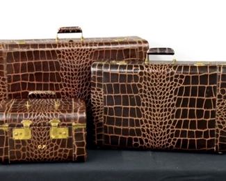 A mid 20th century embossed leather "Alligator" luggage set by Monarch Luggage, New York.  Shades of Brown, includes two larger suitcases with silk linings and a cosmetic case with leather lining and mirror.  Some wear and damage, mirror has losses and lacks left bracket, each monogrammed.  13 to 25 3/4" long.  ESTIMATE $200-400