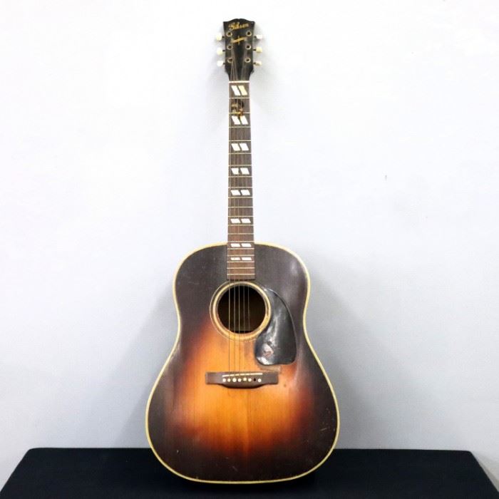 A 1945 Gibson "Banner" flat-top acoustic guitar.  Appears to be a J-45 model, stamped serial #222 inside neck block.  Features a Spruce top with original sunburst finish, Mahogany sides, back and neck, with inlaid Mother-of-Pearl fret markers.  Craquelure and surface wear, particularly worn around pick guard, three large splits to back and one smaller split to front, bridge is lifted, lacks one bridge pin.  41" long.  ESTIMATE $2,000-3,000

