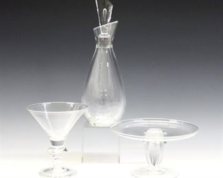 Three pieces of 20th century Steuben tableware.  Includes a teardrop form wine decanter with slanted stopper, a compote with scrolled stem, and a cocktail glass with baluster stem.  Each incised "Steuben".  Minor wear, cocktail glass with small chip to stem and bottom of foot.  3 1/2 to 11" high.  ESTIMATE $300-400
