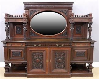 A good quality late 19th century American Black Walnut buffet attributed to Horner Brothers, New York.  Features a tall back with carved decoration and an oval beveled mirror flanked by upper drawers with carved figural columns on a base with three drawers over a pair of central doors with carved panels and end doors over open display shelves all on a molded base.  Older refinishing with wear, restorations to the drawers, imperfections to mirror, lacks upper finials on ends.  97 x 27 x 81" high.  ESTIMATE $1,000-2,000