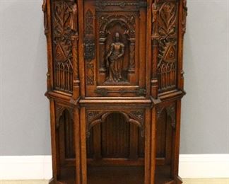 A late 19th century Belgian Gothic Revival cabinet.  Oak construction with carved detail features a shaped top over a central door with forged Iron hardware and figural panel flanked by figural pilasters with carved tracery and linen fold panels, on tall legs with a lower open shelf.  Stenciled and paper label, "Made In Belgium" verso.  Original finish with some minor wear.  34 x 18 x 55" high overall.  ESTIMATE $600-800