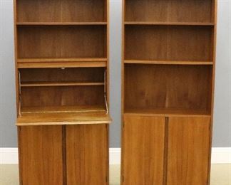 A pair of mid 20th century Teak bookcases.  Each features two to three open adjustable shelves over double-door cabinets with horizontal recessed finger pulls and single shelf.  One with a fold-down writing surface with battery powered lighting and narrow shelf.  Minor wear and some scratches to shelves.  Each 30 1/4 x 12 x 72 1/4" high overall.  ESTIMATE $200-400