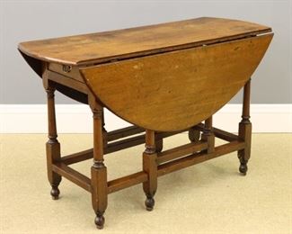 A 19th century British Oak drop leaf table.  Oval molded top with a single drawer, stretcher base with turned legs and double gate leg supports.  Older refinishing with wear and older restoration.  47 1/2 x 19 (46" open) x 30" high overall.  ESTIMATE $600-800