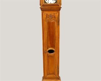 An 18th century Country French grandfather clock.  Cherry case with arched molded hood and conforming door with carved detail, over a long waist door with carved urn and lower pendulum glass on a paneled base with inlaid compass star.  8-day weight driven Morbier movement with bell strike, a round porcelain dial with Roman numerals and embossed Brass bezel with gryphons.  Older refinishing with minor wear, running when cataloged.  95" high.  ESTIMATE $1,000-2,000