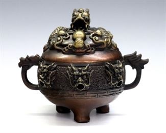 A Chinese Bronze censer.  Round form body with dragon mask decoration and figural lid depicting a dragon chasing flaming pearl, with Copper and Gold tone finish, on short tri-pod legs.  Minor wear, slight pitting, tarnished spot at bottom.  4 1/2" high.  ESTIMATE $200-400
