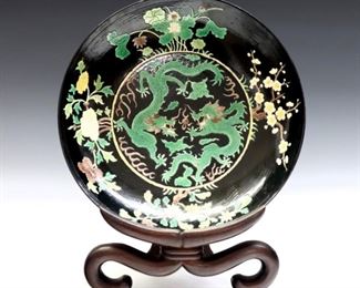 A Chinese Kangxi style Famille Noir porcelain bowl.  Hand-painted and incised decoration depicting two dragons chasing a flaming pearl with floral border, on a scrolled Rosewood stand.  Painted marks.  Some surface wear.  10 1/4" diameter.  ESTIMATE $200-300