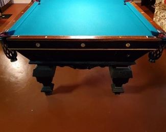 Three-piece slate bed. The traditional green tabletop is in mint shape with no rips or tears. Elegant leather pockets and surround detailing. Includes a full set of balls. Flat tabletop cover.  Brush, 8-ball rack.