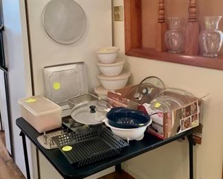 Kitchen items, outside grill pan, meat press, casserole dishes, strainers, plastic bowls with lids.