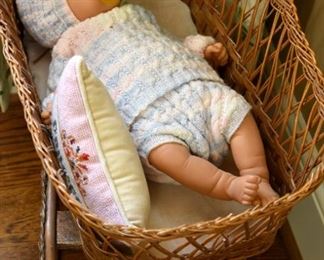 collectible toy baby doll in wicker bassinet