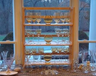 Living Room:  Numerous sets of amber stemware and amber candleholders are displayed among clear glass and porcelain.