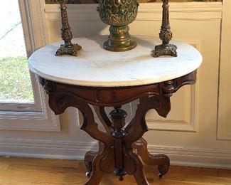 Dining Room:  An antique oval marble top table has detailed carving and is on porcelain casters.  It displays a ceramic artichoke and a pair of resin candlesticks.