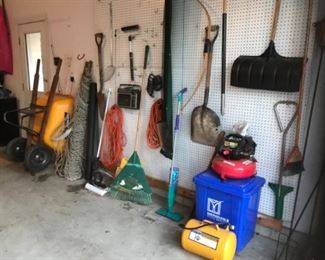 Garage:  A wheel barrow is tilted against the wall but there are also a large net hammock; extension cords; yard tools; CENTRAL PNEUMATIC air compressors: a 3 gallon 100 psi air compressor; and a 5 gallon 125 psi air compressor.