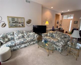 Smith Brothers Floral Sofa and Love Seat in Excellent Condition, Upholstered Round Ottoman, Brass/Glass Coffee Table with Matching Side Table, Various Lamps and Home Décor