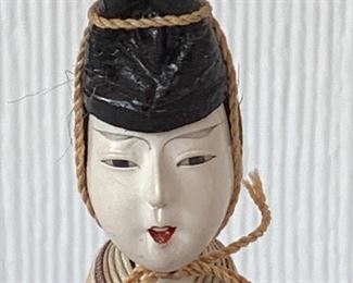 Lovely antique Asian doll figurine sitting on a stand. Her dress has some condition issues including some rips/tears.