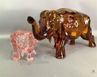 Glass Elephant Covered Candy Dishes
One large amber colored glass covered elephant candy dish. 7"Hx14"Wx4.5"D, no visible cracks or chips. One pink glass elephant covered candy dish. 4.5"Hx8"Wx3"D, large chip on lid piece, chip on elephant also.