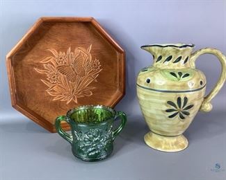 Assorted Houseware
Includes a Mesa International pitcher, decorative wooden serving tray,and a green sugar cup. Small chips in the sugar cup and missing lid.