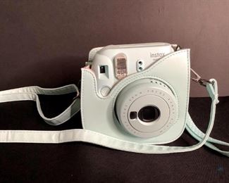 Fujifilm Instax Camera
Light teal colored Fujifilm Instax Mini 9 camera with matching case. Lens has 60mm focus range. Case has shoulder strap attached. Unknown working condition.