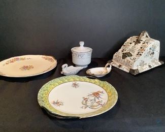 Unique China Pieces
Pieces include a decorative ceramic covered cheese tray with teal, black and amber floral painted design. Stamped Luton TF Sons on the bottom. Tray shows crazing on the surface. Lid has crack on the inside left front and two smaller chips as well.7"Hx7.5"Wx9.5"D One Sugar bowl with lid stamped Fine Porcelain China Claremont Japan on bottom. It has a blue and red floral design with silver tone trim.5"H One loop handled, 3-rest decorative ashtray with cream floral gild. It has ESD Canada Japan stamped on the bottom.4.5" One decorative swan single-rest ashtray with pink and green floral gild. 4" One Moschendorf Bavaria plate as stamped on bottom. It has a floral center with yellow and black trim.10" One cream with blue, orange and pink floral design with 22 carat gold trim. It is stamped Argosy W.S. George Ivory 130D and No 25585 H.M.H. Warranted 22 Carat on the bottom. It has crazing on both sides and two small chips on the bottom rim. 10.5"
