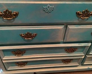 Teal and Wood Colored 3 Pc Furniture Set
All pieces are painted over cherry wood (labels on furniture backs). Small side table has 3 drawers with painted handles. 27"Hx26.5"Wx16"D. Seven drawer rectangular dresser, 33"Hx63"W18"D. Drawers are painted inside as well with brass colored handles.. Queen four poster bed frame is partially painted, some wear/scratches on bedposts. Bedposts have decorative carving and the headboard has cutout design.79"HX63.5"Wx86"D