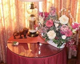 Round decorator table with glass top and beautiful table cloth, runner and floral arrangement.