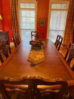 Picture of formal dining room table with wooden chairs around it and 2 leaves inserted.