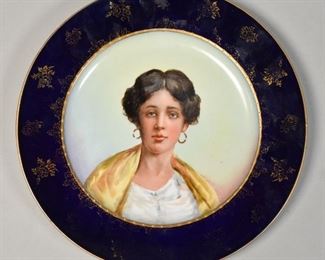 88	Vienna Style Cabinet Plate	Vienna style cabinet plate circa 19th century to early 20th century. Cobalt ground with raised gilt decoration, portrait of a woman in the center. Probably Carl Knoll, Fischern with under glaze "beehive" mark on verso. With green handwritten pattern number and artists initials on verso. Wear to gilt decoration on the edge. 9 1/2" Diameter.

