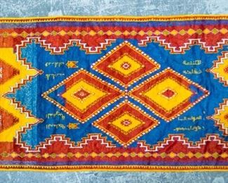 174	Moroccan Rug	Moroccan rug. Red, blue, and yellow, geometric motif, fringe on one side. Arabic writing throughout. Wear on left hand side. 9'7" x 4'8"
