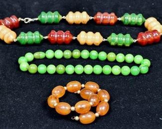 277	Bakelite Necklaces And Bracelet Cherry Amber	Cherry amber, green and butterscotch necklace 23" long. Jade color necklace with screw clasp 16" long. Amber bracelet (missing clasp) 11" long.
