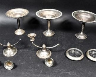 313	Weighted Sterling Grouping	7 pieces of weighted sterling. Preisner compote, pair of Mueck-Carey Co. compotes with openwork rims, Frank M. Whiting & Co. glass coasters with sterling rims, pair of Tarlton candelabra. Preisner compote 6"H x 6"-diameter at bowl. Mueck-Carey compotes bent and dented, one cracked at base; 3 candleholders detached from candelabra, one bent; Preisner compote dented at rim and in bowl; scratches to coasters.
