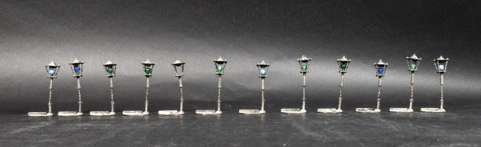 316	Set of 12 Silver Lamppost Place Card Holders	Set of 12 silver lamppost or street light place card holders. Each 2 3/4"H. 158.6 grams total including stones. All unmarked. One missing stone.
