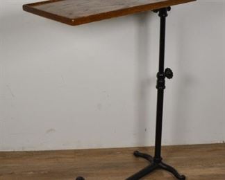 336	Medical Tool Side Table	Medical tool side table. American, Late 19th/Early 20th Century. Oak top pivots on a cast metal stand with four wheeled feet. Height can be adjusted with knobs along the support. Some small scratches to table top. 37" H x 24" L x 14" W
