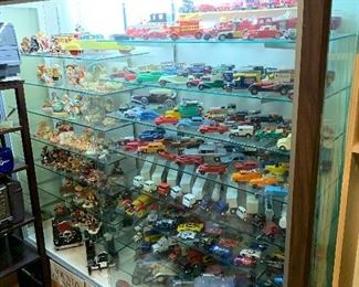 Display cabinet, dinky toys, corgi cars, tootsie toys, matchbox redline and lesney from England, car decanters 