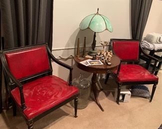 Gorgeous antique red leather chairs with black accent trim. Antique drum table. Light green slag glass lamp. Brass fire hose nozzles, glass water jug