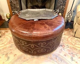 Large round leather ottoman with decorative upholstery tack accent