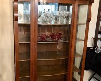 Honey oak Empire style cabinet. Curved glass front, five shaped shelves, original glass. Mirrored top shelf.