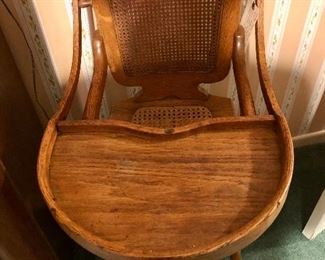 Early 1900s canned tiger oak highchair. Seat and seat back are in perfect condition. On metal rollers. Made in USA.