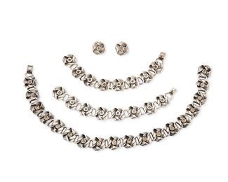 41
A Suite Of Héctor Aguilar Silver Jewelry
1948-1962; Taxco, Mexico
Each stamped: HA [conjoined] / Taxco; Further variously stamped: [Eagle 9] / .940 / 940 / Mexico; Earring stamped: Silver
Comprising a matching set formed of silver knotted or ribbon motif links consisting of a necklace (16.5" L x 0.75" H), two clasp bracelets (7.5" L and 7.75" L x 0.75" H), and a pair of screw-back earrings (0.875" H)

5 pieces
257.5 grams gross
Estimate: $800 - $1,200